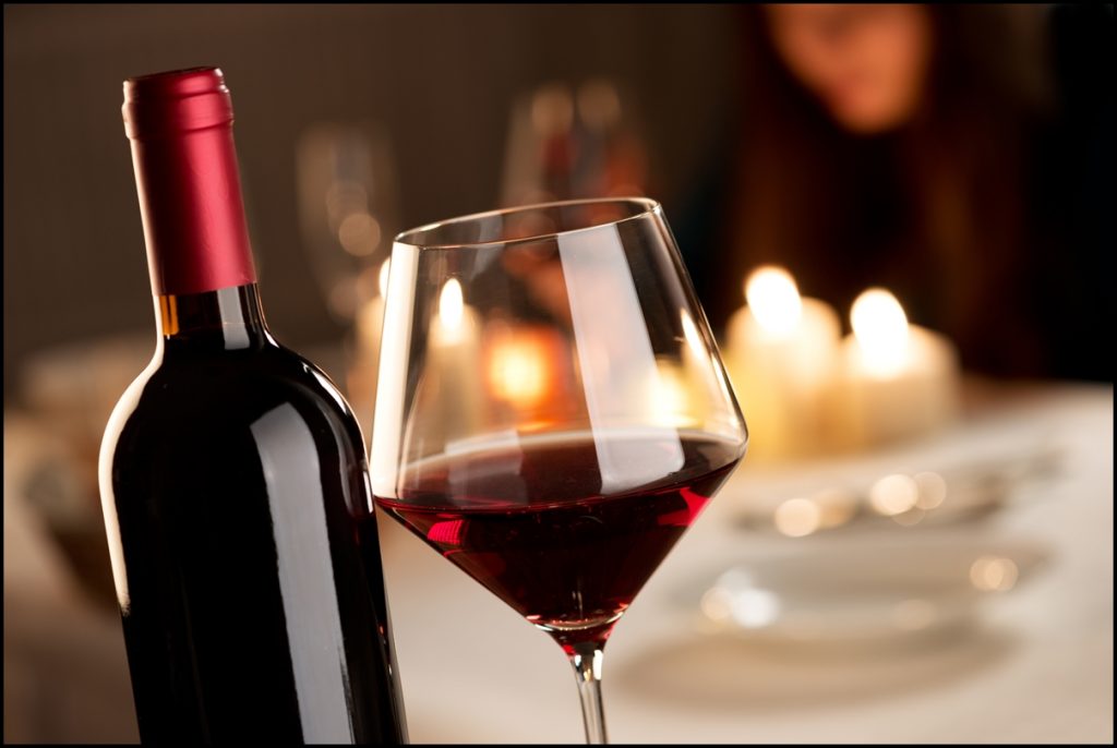 Image Shows A Glowing Red Wine Bottle with Glass