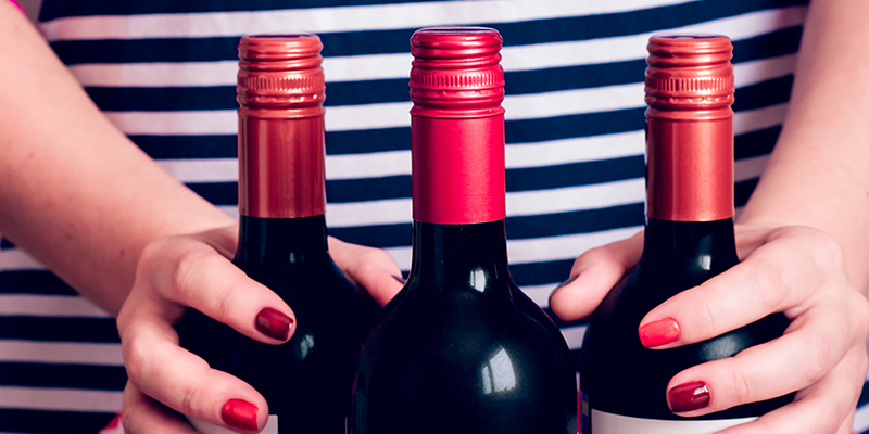 An Image of Three Red-Wine Bottles Were Hold By A Woman