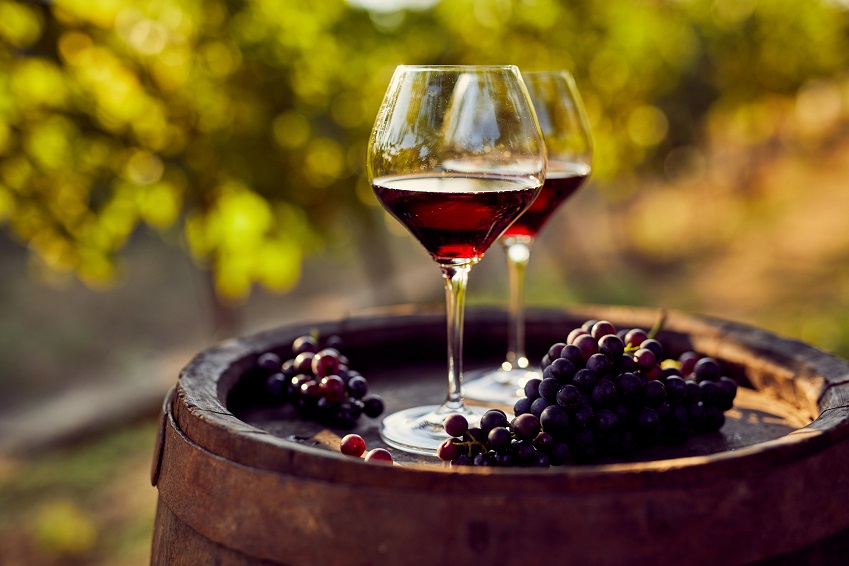 Two Glass of Red Wine Placed on a drum with grapes